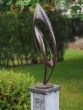 Bronzeskulptur Abstrakt mit brauner Patina auf einem Sockel im Garten 