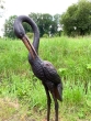 Bronzeskulptur Reiher mit gesenktem Kopf von vorne auf einem Feld
