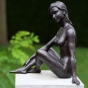 Bronzeskulptur Sitzende Junge Frau mit brauner Patina auf Säule im Garten 