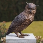 Bronzeskulptur Sitzende  Eule mit brauner Patina auf einer Säule im Garten 