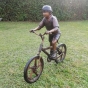 Bronzeskulptur "Liam auf Fahrrad" auf einer Wiese
