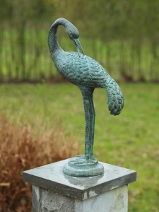 Bronzeskulptur Reiher mit grüner Patina auf Sockel im Garten 