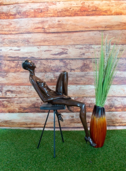 Bronzeskulptur Sitzende Pia auf einem Stuhl mit brauner Patina von der Seite 
