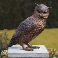 Bronzeskulptur Sitzende  Eule mit brauner Patina auf einer Säule im Garten 