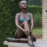 Bronzeskulptur Sitzende Ballerina mit grün brauner Patina im Garten 