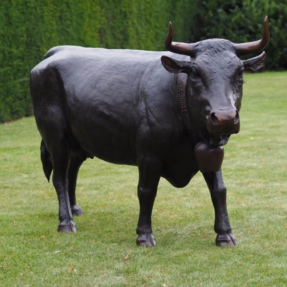 Bronzeskulptur Stehender Bulle mit brauner Patina auf einer Wiese 